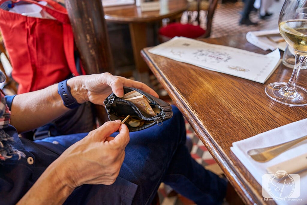 Andi taking coins out of her double sided wallet in Paris