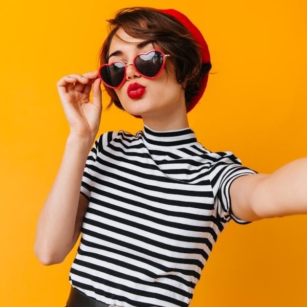 girl in blue and white striped shirt and red beret with red sunglasses
