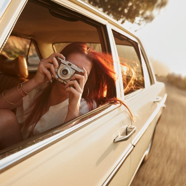 girl in car holding camera hero
