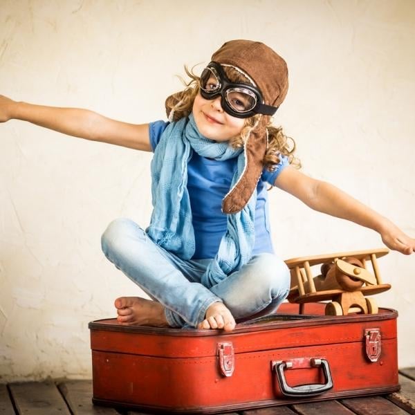 little girl in flight gear on suitcase copy